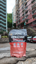 VOW Strawberry Creatine Chews on a stone ledge with Hong Kong residential buildings behind